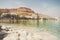 Blue water in the dead sea in the foreground on the background of the resort town of Ein Bokek in the middle of the desert in