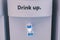 Blue water gallon with word `It`s free,Drink up,Stress?`on electric water cooler