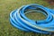 Blue water hose rolls on the lawn