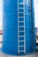 Blue water tower with a white staircase and a black hose