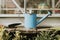 Blue watering can with trowel on wooden table