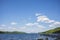 The blue waters of Otsego Lake in Cooperstown, New York, on a sunny summer day with cumulus clouds in the sky, photographed near a