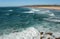 Blue waves and sandy beach with scenic cliffs and seaside of Portugal. Ocean waves on peaceful and sunny area of Algarve