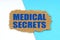 On a blue and white background lies a piece of cardboard with the inscription - Medical Secrets