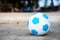 The blue and white ball rests on the beach  on the sand.