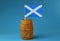A blue and white flag of Scotland, part of Great Britain, on wooden stick in wooden barrel.