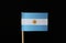 A blue and white national flag of Argentina on toothpick on black background. A horizontal triband of light blue and white with th