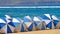 Blue and white parasols on a sunny but windy day by the sea,