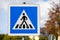 Blue white road sign on a pedestrian crossing with blurred background.