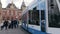 Blue and white tram traveling through the square in front of the Amsterdam Central