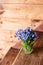 Blue wildflowers in a glass cup on a wooden background. Forget me nots.