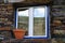 Blue window with blue trim and a rustic stone wall