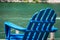 A blue wooden lawn chair on the waterfront riverwalk on a sunny day