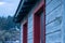 Blue wooden siding and red trimmed windows aged and distressed from time and weather