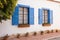 blue wooden window shutters on whitewashed spanish revival building