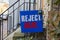 A blue yard sign that says Reject Hate is placed on the front yard of an old building