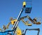 Blue and yellow aerial work platform against clear blue sky