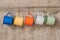 Blue-Yellow-Orange-White-Green tin cup hanging on stainless rail on cement wall background