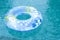 Blue and yellow pool float, ring floating in a refreshing blue swimming pool. Empty swimmig pool. Copy space banner.