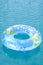 Blue and yellow pool float, ring floating in a refreshing blue swimming pool. Empty swimmig pool. Copy space banner.