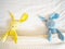 Blue and yellow rabbit doll laying on white bed under cream blanket pink polka dot pattern