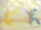 Blue and yellow rabbit doll laying on white bed under cream blanket pink polka dot pattern