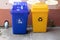 Blue and yellow trash cans. Colorful plastic bins for different waste types