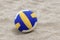 Blue and Yellow Volleyball on the beach and footprint on the sands