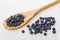 Blueberries on bamboo spoon, scattered blueberry on table