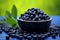 Blueberries in a black bowl. Biologically active supplement - pills for healthy eyes on green luscious background