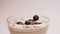 Blueberries fall in vegan yogurt in a transparent glass, healthy breakfast. Add the berry-shaped vitamins to the milk