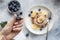 Blueberries in a female hand with a beautiful nude manicure, over a table with pancakes.