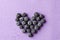 Blueberries heart on purple from above