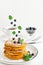 Blueberries and mint leaves falling on a stack of pancakes. American dessert