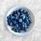 Blueberries on oatmeal in a bowl on white marbled background in top view layout, bright blue berries and oats are a healthy nutrit