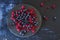 Blueberries, redcurrants and raspberries fruits on a black slate dish