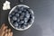 Blueberries in a small white bowl with refined sugar pieces. On a black stone board. Summer berry. Yummy