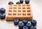 Blueberries on top of sweet waffle on plate closeup