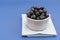 Blueberries in white bowl over blue background, fresh berry over blue background