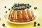 blueberry bundt cake with icing on a yellow background