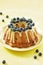 blueberry bundt cake with icing on a yellow background