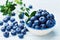 Blueberry or great bilberry in bowl on blue rustic background. Organic superfood and healthy nutrition.