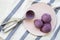Blueberry ice cream balls with icecream scoop on a pink plate over striped napkin, top view. From above, flat lay