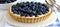 Blueberry mini tart on white cutting board with vintage teaspoons, top view food photography
