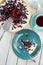 Blueberry open pie on blue plate with metal spatula close up with cup of black tea and tea pot