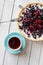 Blueberry open pie with cup of black tea on bright painted wood background