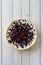 Blueberry open pie with cup of black tea on bright painted wood background overhead view