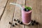 Blueberry smoothie with berries, mint and straw over rustic wood