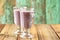 Blueberry smoothie in two glass Irish mugs on old wooden table w