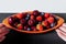 Blueberry, Strawberry and cherry in faience bowl with fruit  and hands, geometric background